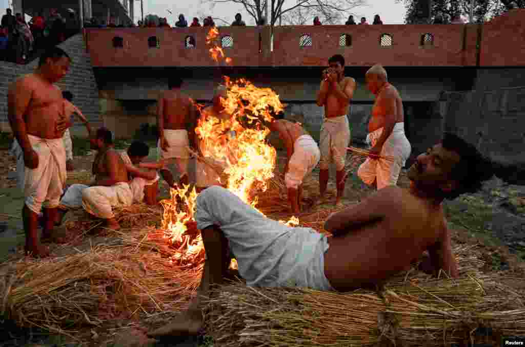 Devotees gather beside a fire before taking a holy bath at the Hanumante River during the final day of the month-long Swasthani Brata Katha festival in Bhaktapur, Nepal.