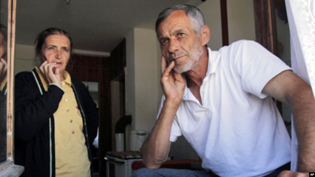 Bosnian Muslim couple Halida, 52, left, and Abaz Dudic, 56, an unemployed former war camp prisoner, stand near a window inside their shelter at the collective center for refugees near the northern Bosnian town of Zivinice, 130 kms north of Sarajevo, where