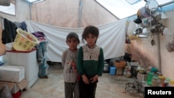 FILE - Jumana and Farhan al-Alyawi, 8-year-old displaced Syrian twins from east Idlib, pose for a picture in a tent at Atmeh camp, near the Turkish border, Syria, June 19, 2020.