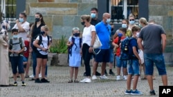 FILE - In this Wednesday, Aug. 12, 2020 file photo, parents wait with children on the schoolyard for the start of their first day at a school in Gelsenkirchen, Germany. (AP Photo/Martin Meissner, File)