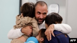 A handout picture released by the spokesperson's office of Schneider Children Medical Center in Petah Tikva on November 26, 2023 showing Avihai Brodetz hugging his children, after their release by Hamas amid an exchange operation of hostages against Palestinian prisoners.