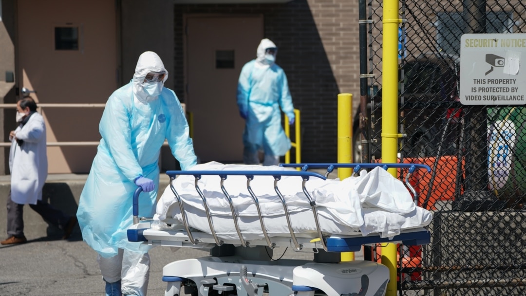 在纽约布鲁克林区一家医院外,工作人员把遗体送入一辆被当作临时停尸房的冷冻卡车。(2020年4月6日)