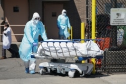 Bodies are moved to a refrigeration truck serving as a temporary morgue at Wyckoff Hospital in the Borough of Brooklyn on April 6, 2020 in New York.
