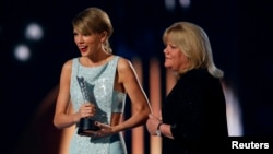 Taylor Swift menerima Milestone Award dari ibunya, Andrea, dalam 50th Annual Academy of Country Music Awards di Arlington, Texas (19/4). (Reuters/Mike Blake)