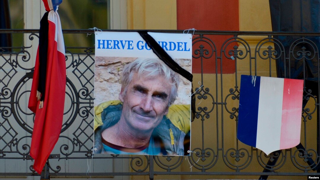 A portrait of mountain guide Frenchman Herve Gourdel hangs near a French flag outside the town hall in Saint-Martin-Vesubie, Sept. 25, 2014.