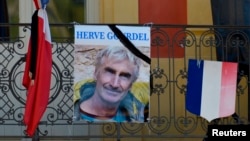 A portrait of mountain guide Frenchman Herve Gourdel hangs near a French flag outside the town hall in Saint-Martin-Vesubie, Sept. 25, 2014.