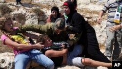 FILE - Nariman Tamimi and her daughter Ahed try to free her son Mohammed from an Israeli soldier during a protest near the West Bank village of Nebi Saleh, Aug, 28, 2015. Israeli Cabinet ministers have proposed legislation that seeks to outlaw photographing Israeli soldiers "for the sake of shaming them," a ban rights groups say would amount to government censorship.