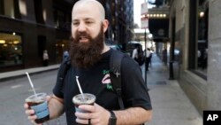 Adam Taylor, a sound engineer from Las Vegas, carries two glasses of iced coffee, responds to a question about new research showing that drinking coffee may boost chances for a longer life, even for those who down at least eight cups daily, July 2, 2018, in Chicago, Illinois.