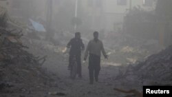 Men are seen inspecting damage that was reportedly caused by shelling from Syrian government forces, along a street in the Duma neighborhood of Damascus, Nov. 17, 2013.