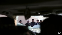 Afghan civilians watch over site of Friday's suicide attack, shooting in Kabul, Jan. 18, 2014.