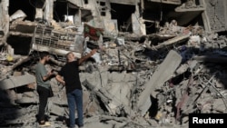 People stand on the rubble at the site of the Israeli airstrike that killed Lebanon's Hezbollah leader Sayyed Hassan Nasrallah on Friday, in Beirut's southern suburbs, Lebanon, Sept. 29, 2024. 