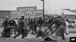 ARCHIVO - Un policía de Alabama golpea con un garrote a John Lewis, activista de derechos civiles, para disolver una marcha en Selma, Alabama, el 7 de marzo de 1965.