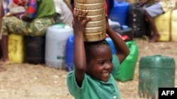 Une jeune garçon porte de l'eau dans un camp de déplacés à 180 km de Maputo, le 16 mars 2000.