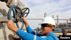 FILE - A worker checks the valve of an oil pipe at Basra refinery in Basra province, March 1, 2014. 