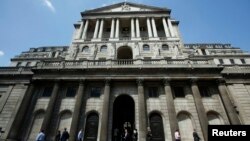 FILE - Pedestrians walk past the Bank of England in the City of London.