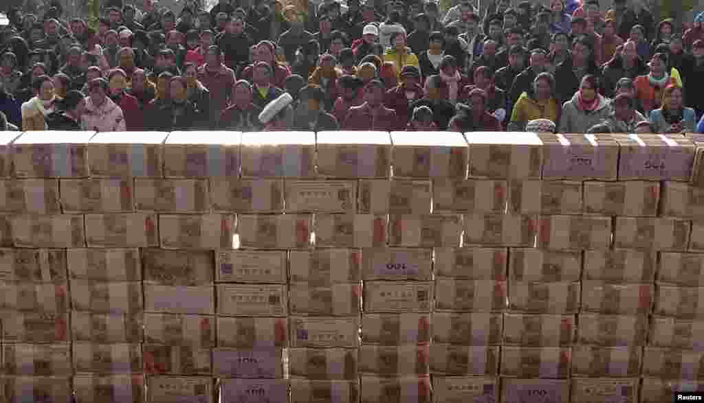 Villagers wait to collect their year-end bonus at Jianshe village, Liangshan, Sichuan province, China, Jan. 14, 2014. About 13,115,000 yuan ($2,169,221) were placed in the middle of a square before being distributed as bonus to around 340 villagers in return for their investment in the planting and breeding co-operative in the village in 2013.