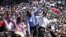 Kenya's former Education Minister William Ruto, center left, Kenya's Deputy Prime Minister Uhuru Kenyatta, center, and Kenya's Vice President Kalonzo Musyoka, center right, wave to thousands of people during a prayer rally at Uhuru Park, Kenya, Monday, Ap