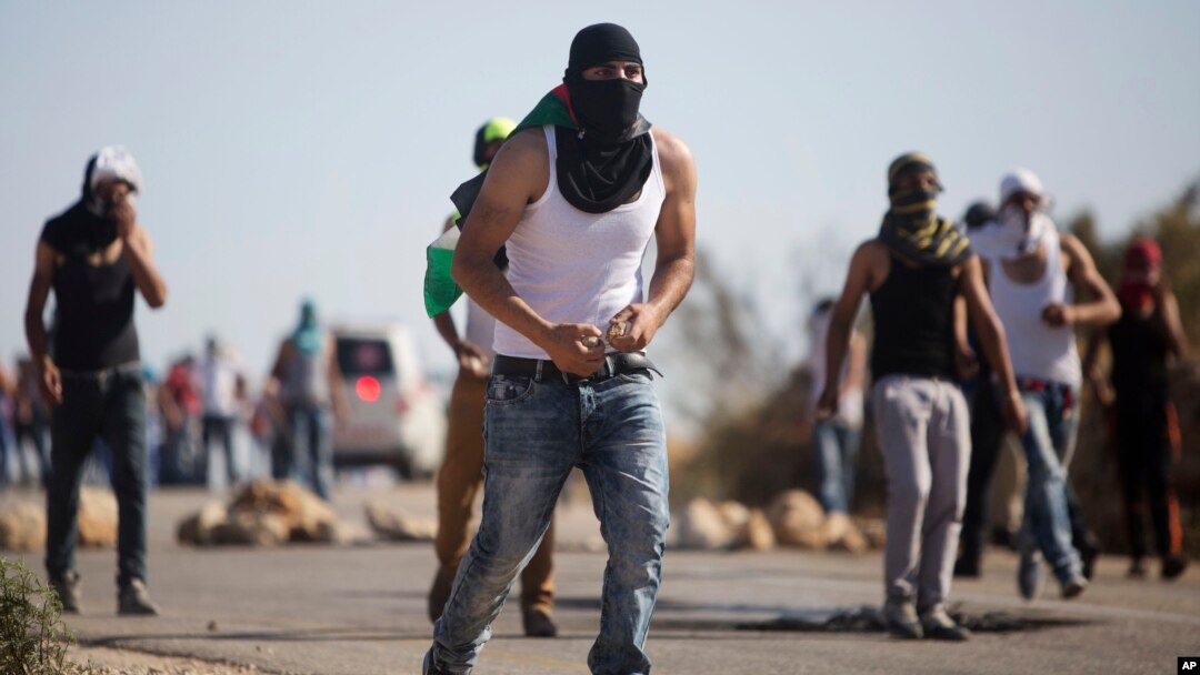 Palestinian demonstrators throw stones toward Israeli security forces during clashes after the funeral of Palestinian Saed Dawabsheh who died after an arson attack on his family's home, in the West Bank village of Duma near Nablus, Aug. 8, 2015. 