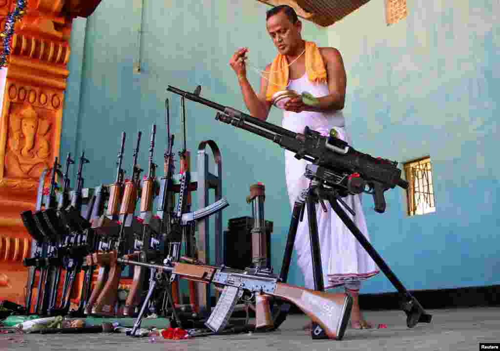 A Hindu priest blesses weapons belonging to Tripura State Rifles during the Vishwakarma Puja, or the festival of the Hindu deity of architecture and machinery, in Agartala, India.