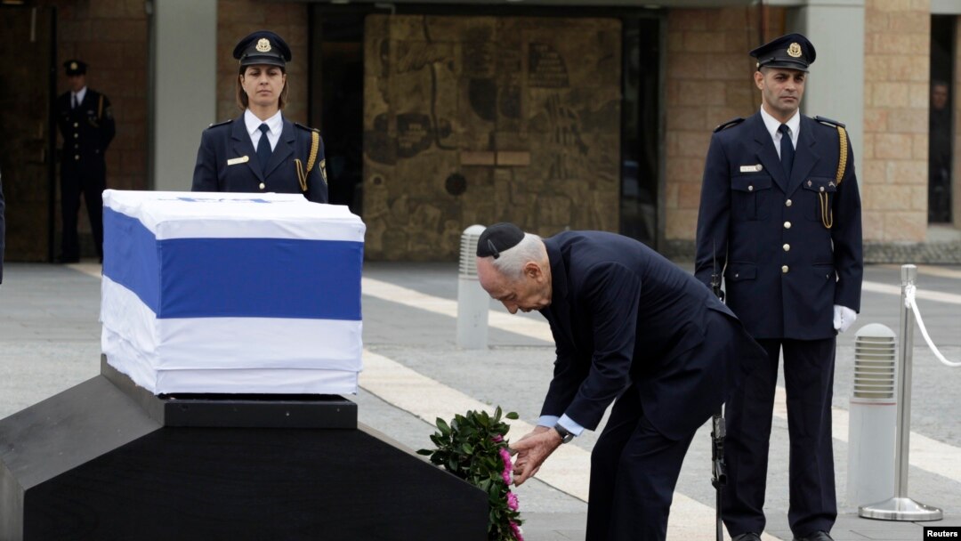 Israel's President Shimon Peres (C) lays a wreath near the flag draped coffin of former Israeli prime minister Ariel Sharon as he lies in state at the Knesset, Israel's parliament, in Jerusalem, Jan. 12, 2014. 