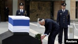 Israel's President Shimon Peres (C) lays a wreath near the flag draped coffin of former Israeli prime minister Ariel Sharon as he lies in state at the Knesset, Israel's parliament, in Jerusalem, Jan. 12, 2014. 