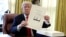 FILE - President Donald Trump displays the $1.5 trillion tax overhaul package he had just signed, Dec. 22, 2017.