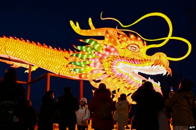 People gather to look at a giant dragon figure at a park in Beijing on Feb. 9, 2024, which marks the eve of the Lunar New Year. This will be the Year of the Dragon.
