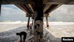 Children play under the pier at Jacksonville Beach ahead of Hurricane Dorian in Jacksonville, Florida, Sept. 3, 2019. 