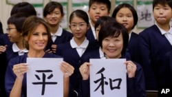 La primera dama de EE.UU. Melania Trump y Akie Abe, esposa del primer ministro japonés Shinzo Abe, muestran una imagen de caligrafía japonesa que hicieron durante una clase de niños de cuarto grado en la escuela primaria Kyobashi Tsukiji de Tokio, Japón. Nov.. 6 de 2017.