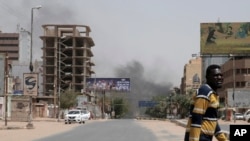 Un homme marche alors que de la fumée s'élève d'un quartier de Khartoum, au Soudan, le samedi 15 avril 2023.