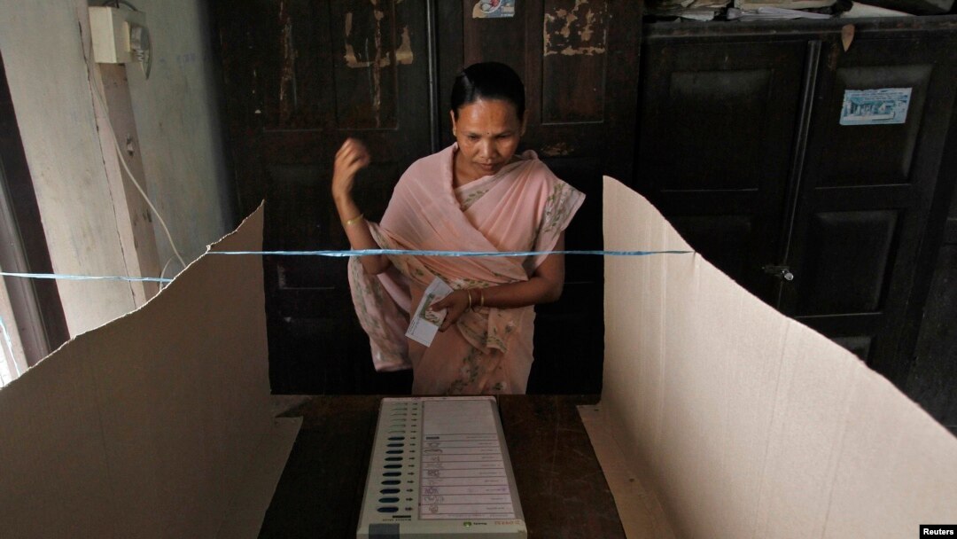 Seorang pemilih bersiap memberikan suaranya menggunakan mesin pemilih elektronik di sebuah TPS Dhekiajuli di distrik Sonitpur, negara bagian Assam, India timur laut.