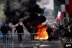 FILE - Members of the Gendarmerie stand in front of fences and a fire as protesters linked to the Yellow Vests movement (unseen) take part in a demonstration on the side of the annual Bastille Day ceremony, July 14, 2019, on the Champs-Elysees.