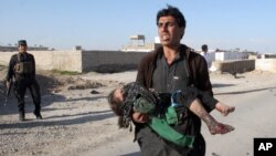 FILE - An Afghan man carries a wounded girl at the side of a suicide attack that killed civilians and a policeman in Lashkar Gah, the capital of Helmand province, south of Kabul, Afghanistan, March 16, 2015.