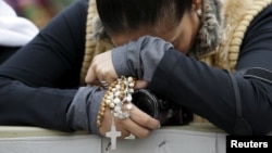 FILE - A woman prays as Pope Francis leads the weekly audience in Saint Peter's Square, at the Vatican, Nov. 18, 2015.