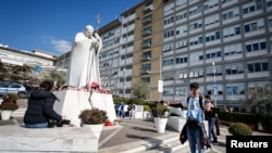 Un hombre utiliza su teléfono junto a la estatua del fallecido Papa Juan Pablo II, frente al Hospital Gemelli, donde el Papa Francisco está ingresado para recibir tratamiento, en Roma, Italia, el 22 de febrero de 2025. (Foto: Reuters)