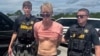 Suspected Trump golf course gunman Ryan W. Routh stands handcuffed after his arrest during a traffic stop near Palm City