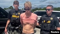 Suspected Trump golf course gunman Ryan W. Routh stands handcuffed after his arrest during a traffic stop near Palm City