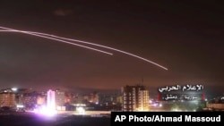 FILE - This photo provided by the government-controlled Syrian Central Military Media shows missiles rise into the sky as Israeli airstrikes hit air defense positions and other military bases, in Damascus, Syria, in May 2018. 