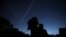 A woman holds her son while they view Jupiter and Saturn during a planetary conjunction, as they appear close together in a rare celestial event in Houston, Texas, Dec. 21, 2020.