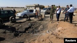 FILE- Army personnel look at the site of an explosion at an army checkpoint in Barsis, east of Benghazi, Libya, June 12, 2014.