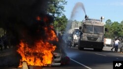 A police truck extinguishes a burning highway maintenance vehicle, after police dispersed protesters blocking a toll road and encouraging drivers not to pay, in Zambrano, north of Tegucigalpa, Honduras, Oct. 3, 2016. Groups organized by opposition political party LIBRE blocked major highways in multiple locations to protest against highway tolls.
