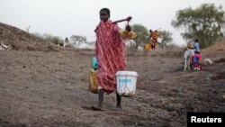 A woman carries water from a water hole near Jamam refugee camp in South Sudan's Upper Nile State, March 10, 2012.