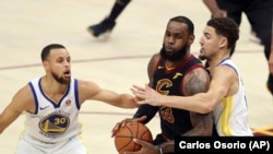 LeBron James aux prises avec Klay Thompson et Stephen Curry (30 ans) des Golden State Warriors (Photo AP / Carlos Osorio- Archives)