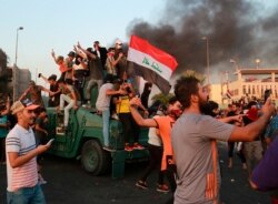 Anti-government protesters take over a security forces armored vehicle before they burn it during a demonstration in Baghdad, Iraq, Oct. 3, 2019.