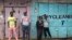 Young Kenyan men hang out in front of closed shops in Nairobi's Kibera slum Monday, Aug. 14, 2017. Kenyan opposition leader Raila Odinga urged his supporters to skip work on Monday to protest what he charged were rigged elections that gave victory to President Uhuru Kenyatta.