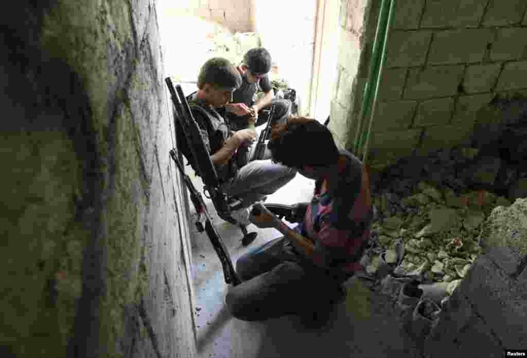 Free Syrian Army fighters check their weapons as they take positions during what they say is an offensive against forces loyal to Syria&#39;s President Bashar al-Assad.