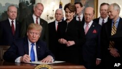 President Donald Trump signs a presidential memorandum imposing tariffs and investment restrictions on China in the Diplomatic Reception Room of the White House, March 22, 2018, in Washington. 