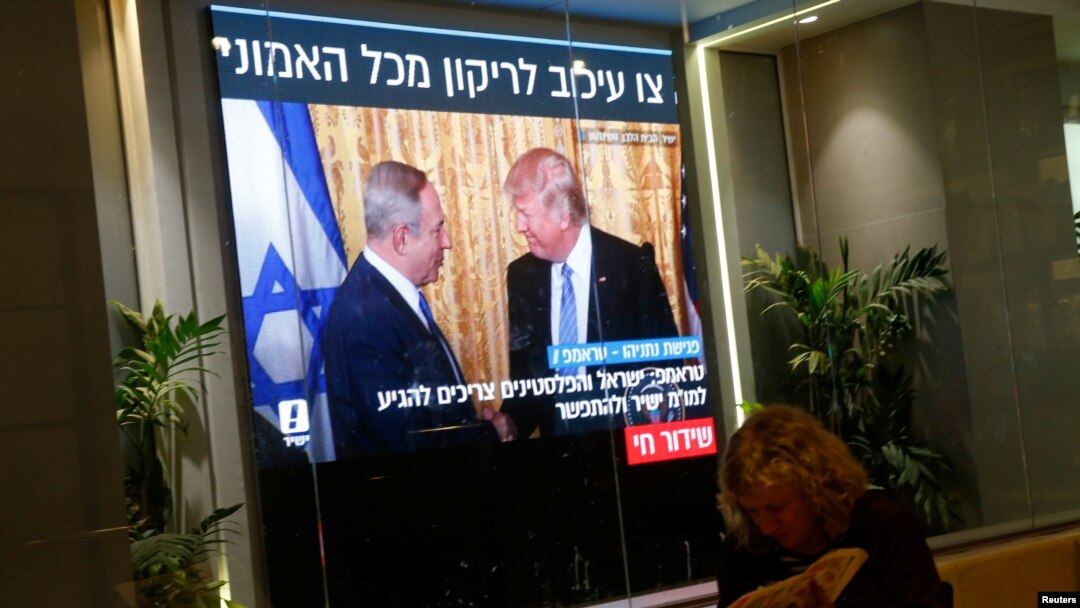 Seorang perempuan membaca koran di sebuah kafe di Tel Aviv sementara layar televisi di dekatnya memperlihatkan gambar pertemuan antara Presiden AS Donald Trump dan Perdana Menteri Benjamin Netanyahu di Washington (15/2). (Reuters/Baz Ratner)