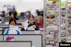 Para pekerja memproses surat suara melalui pos di Pusat Pemrosesan Surat Suara Los Angeles di California, AS, 29 Oktober 2024. (Foto: Mike Blake/Reuters)