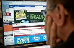 FILE - A journalist looks at a computer screen with webpages arranged to show Cyber Monday deals by various online retailers, Nov. 26, 2018, in New York.